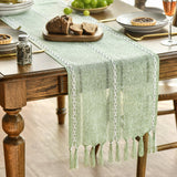 Traversă de masă stil rustic Boho cu ciucuri Artoid Fashion 33x143 cm – Verde Salvie